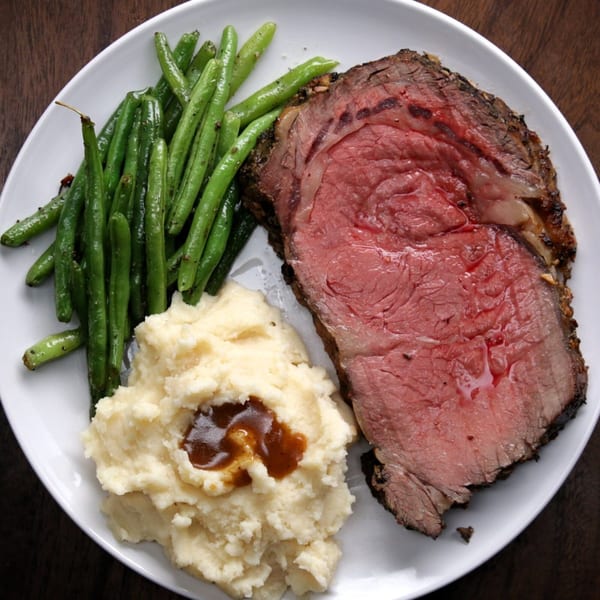 Tony M's prime rib with green beans and mashed potatoes, drizzled with gravy.