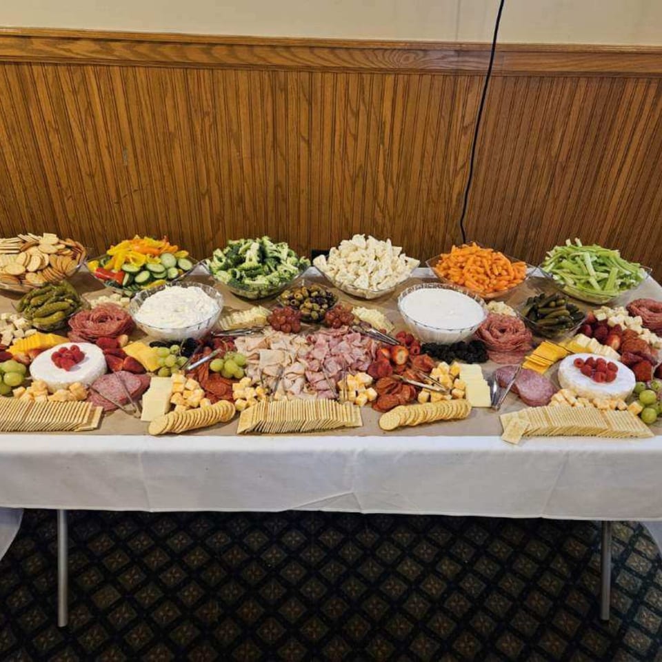 A long buffet table laden with a variety of Italian appetizers, including meats, cheeses, crackers, and vegetables.