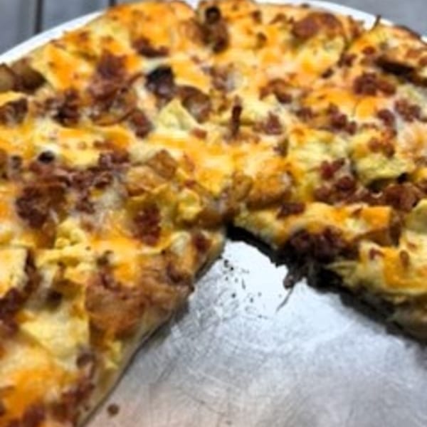 Tony M's breakfast pizza with scrambled eggs, cheese, and sausage, with one slice removed.