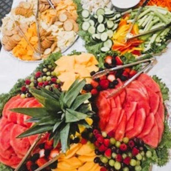A vibrant buffet spread featuring fresh fruit, cheese and crackers, and vegetable platters.
