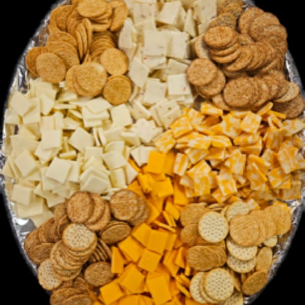 A platter with four sections of crackers and cubed cheeses, including cheddar and pepper jack.