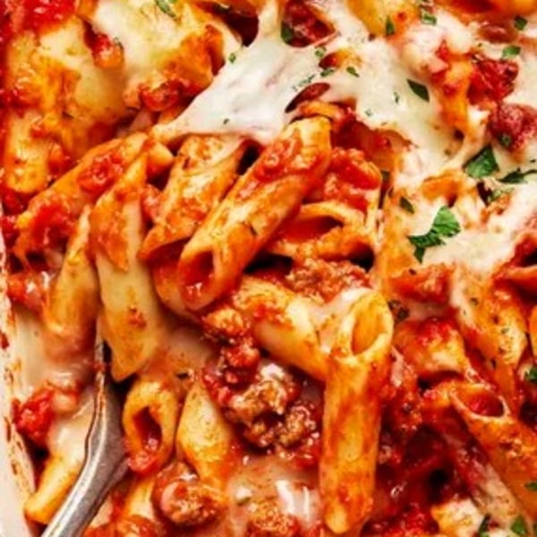 Close-up of baked ziti with melted cheese, rich red sauce, and ground meat, garnished with parsley.