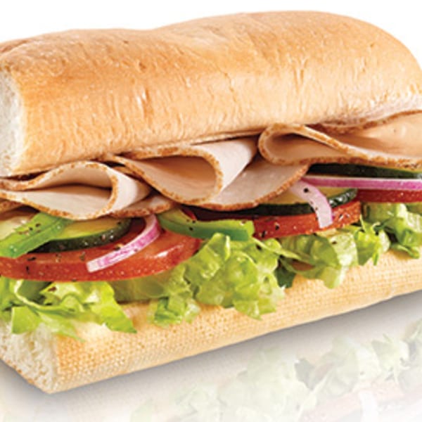 A large Italian sub sandwich with turkey, lettuce, tomatoes, onions, and cucumbers.