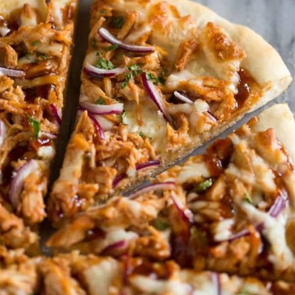 Close-up of three slices of BBQ chicken pizza with red onions and cilantro.