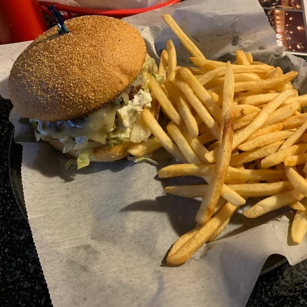 A burger with melted cheese and lettuce, served with a side of golden french fries.