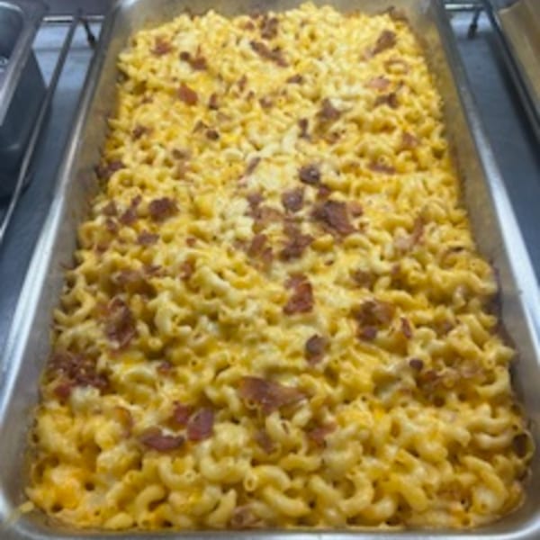 A large tray of baked macaroni and cheese with bacon bits, ready to serve.
