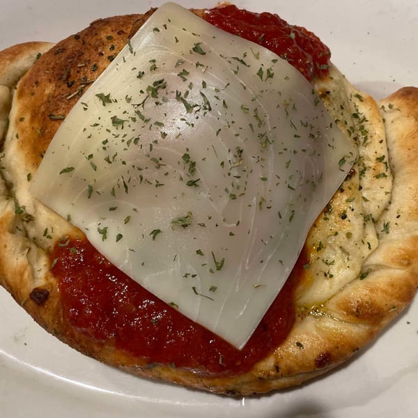 Tony M's Italian calzone with marinara sauce, melted cheese, and herbs on a white plate.