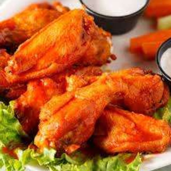 Tony M's buffalo chicken wings with ranch dressing, celery, and carrots on a bed of lettuce.